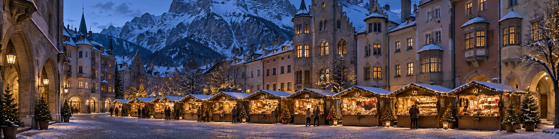 Christkindlmarkt zwischen gotischen Erkerhäusern, dahinter eine verschneite Felswand
